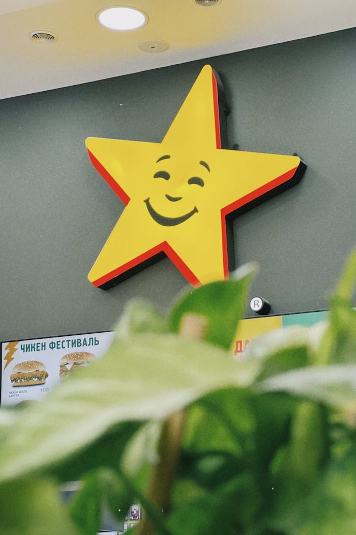 Close-up of Carl's Jr star logo with menu and plants in an Almaty, Kazakhstan restaurant.